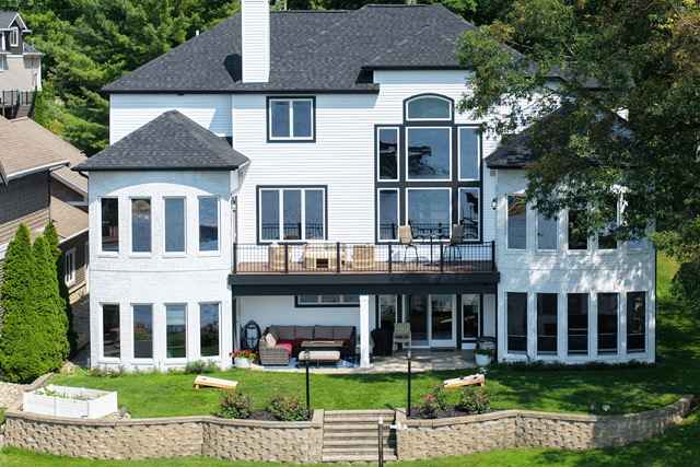 Rear elevation of the estate above a tiered stone terrace and lawn running down to the shoreline