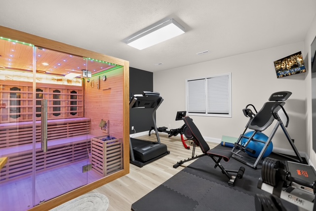 The private gym with cardio and strength equipment beside a glass-front infrared sauna