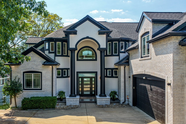 Daytime front-elevation view of the estate with columned entry, arched transom and attached garage