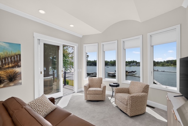 A sitting room with swivel chairs, a bay of lake windows and a sliding door onto the deck