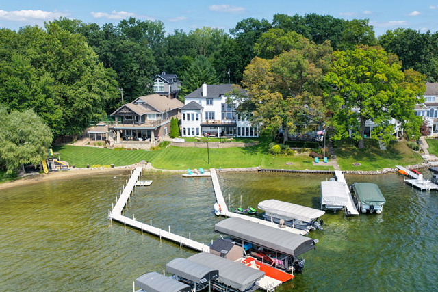 The estate seen from over the water, with lawn, shoreline and private docks in the foreground