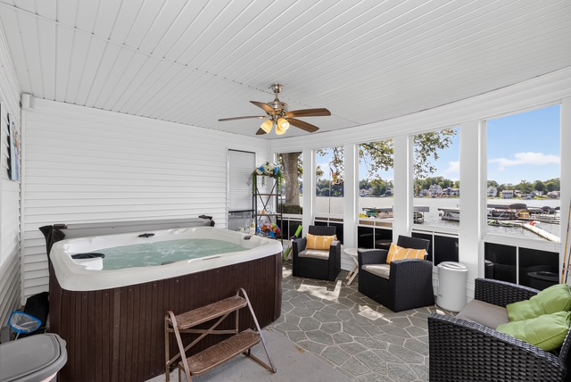 The screened lakefront spa room with Jacuzzi, lounge seating and windows onto the water